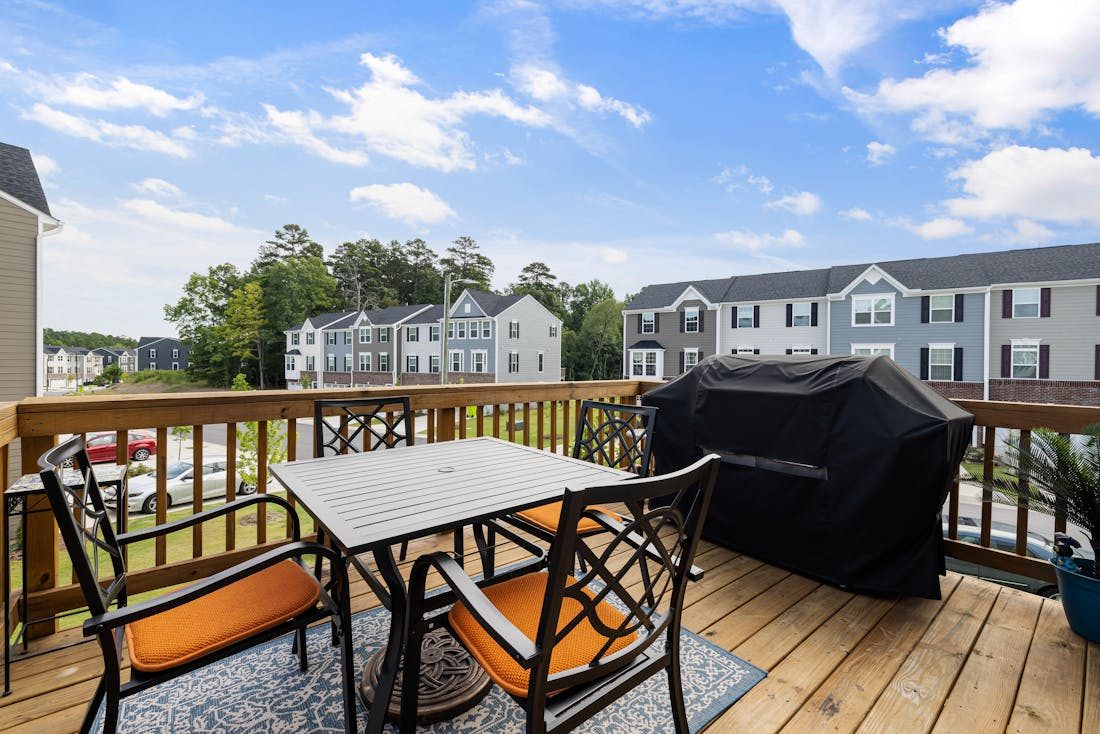 Backyard deck with furniture, grill, and suburban view
